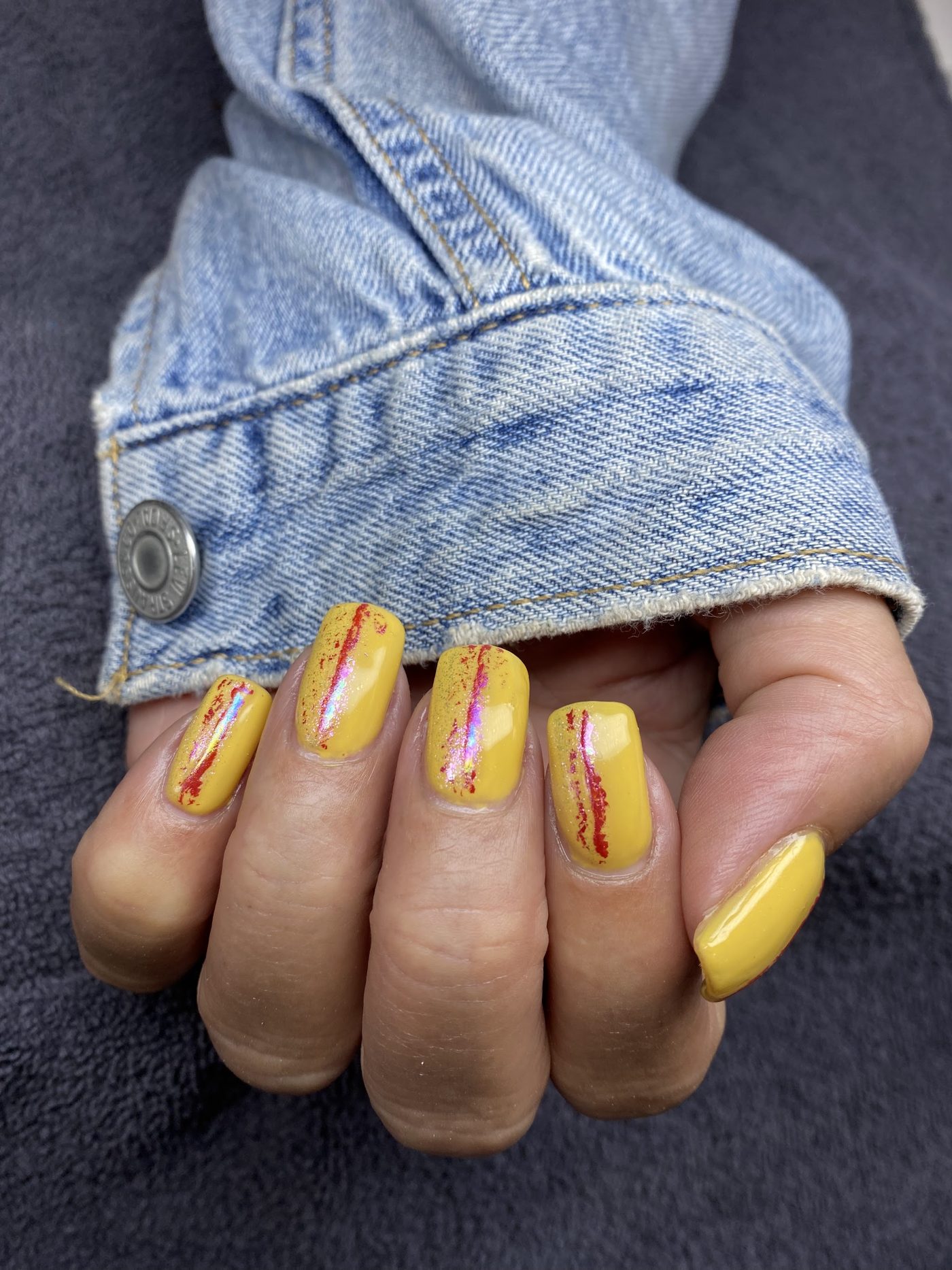 Gele nagels met rode en gouden nail art strepen